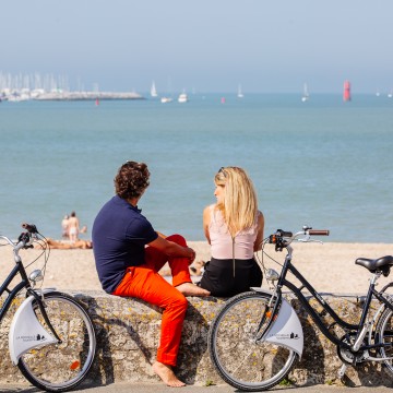 Couple et vélos devant la plage de La Concurrence