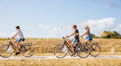 Femme et deux enfants en balade à vélo dans les champs
