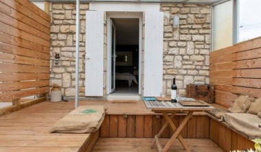 Petite terrasse enfoncée, en bois avec table et coussins. Terrasse - Les Ecologites